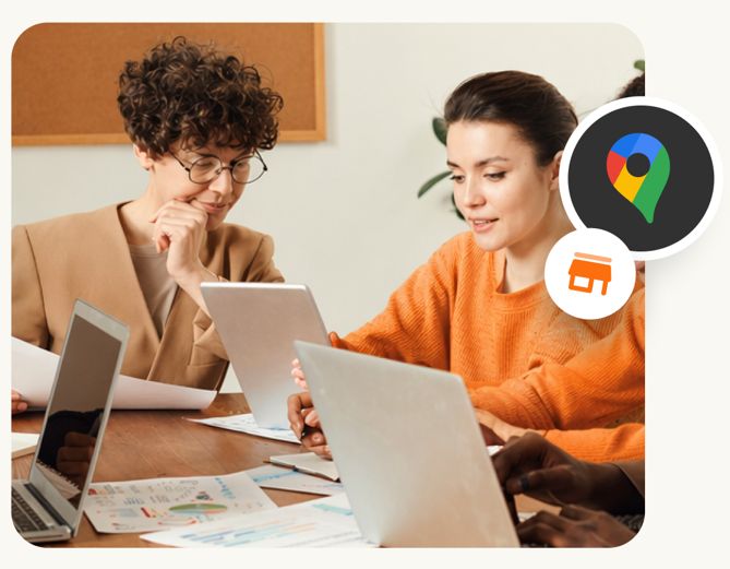 Dos chicas trabajando en mesa con ordenadores en una agencia seo local
