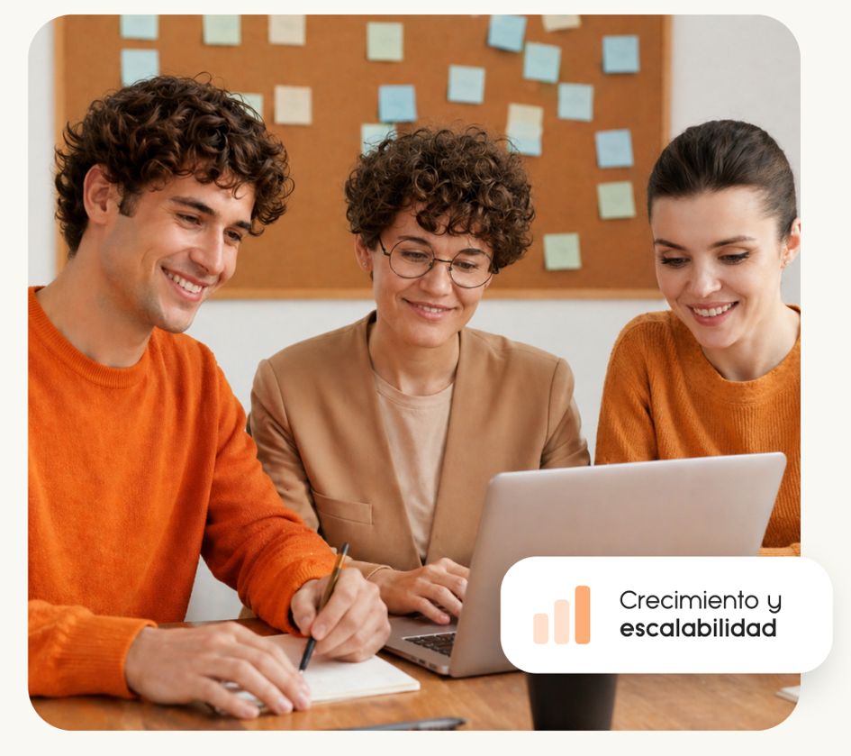 Tres personas sentadas en una mesa mirando el ordenador de una agencia de mkt